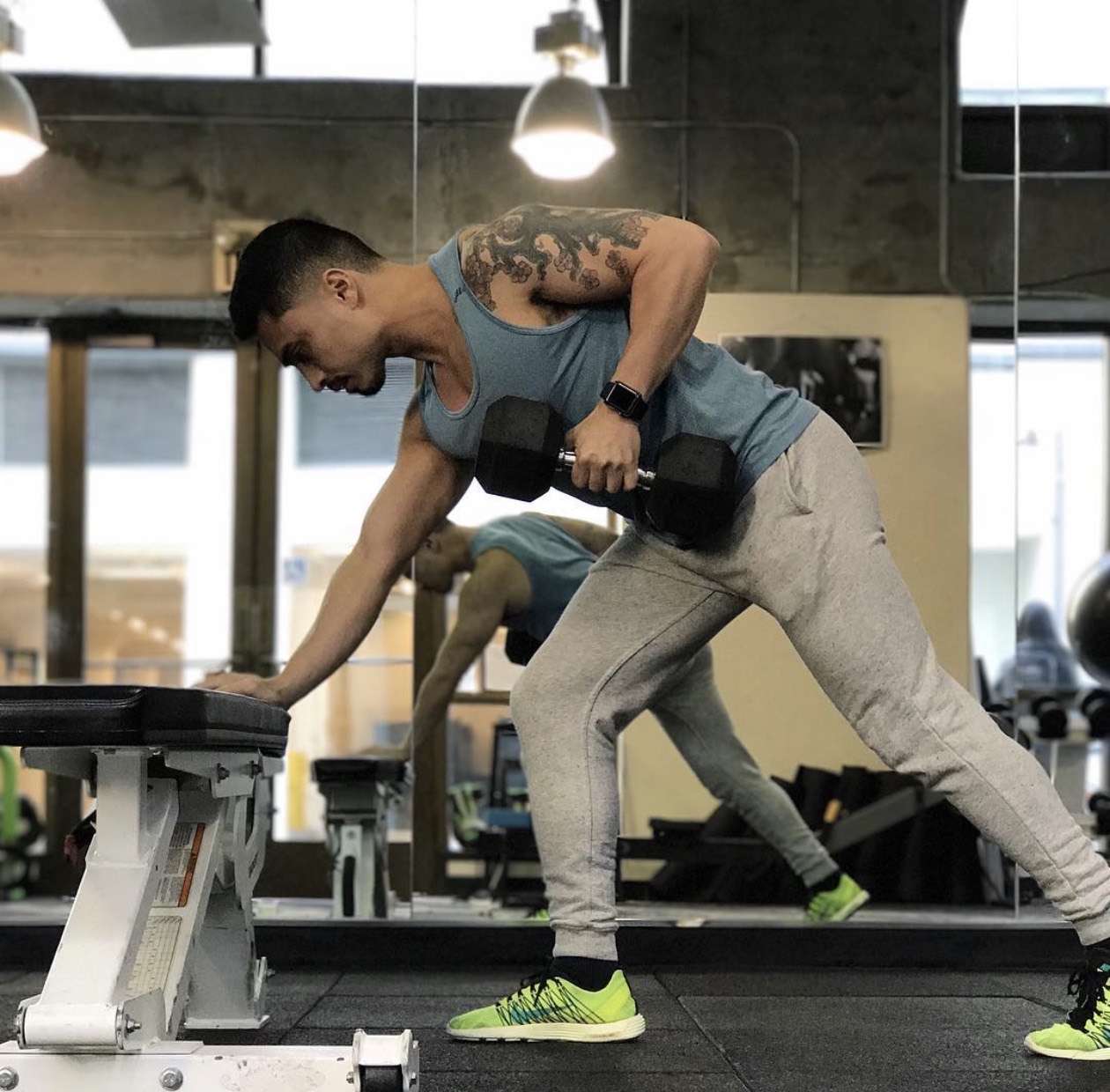 Benjamin performing a one-arm dumbbell row in the gym